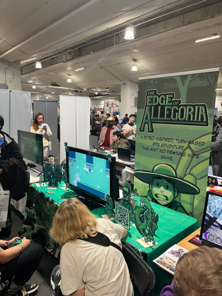 Booth for 'The Edge of Allegoria' at a gaming expo, featuring a themed display with game-inspired decor, interactive gameplay, and a branded banner.